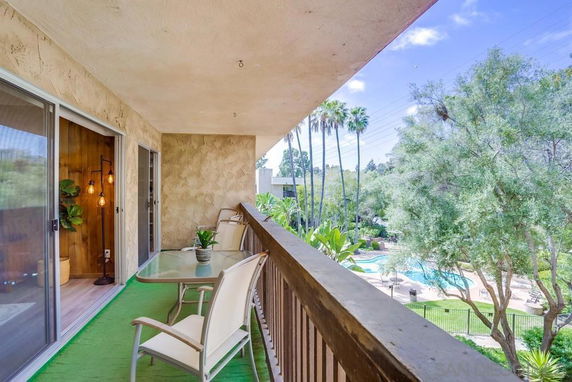 Balcony view overlooking a swimming pool and lush greenery.