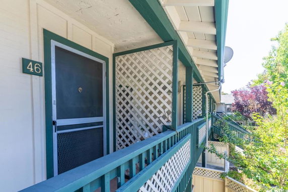 Front view of a building with a green and white exterior and a visible screen door numbered 46.