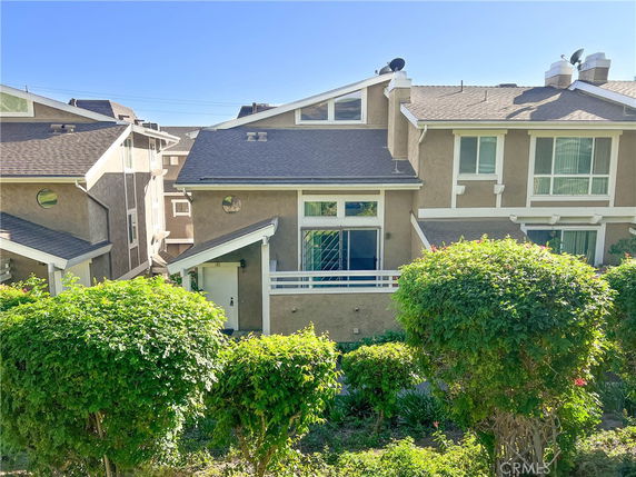 Front view of a multi-story residential building with a sloped roof and satellite dishes.