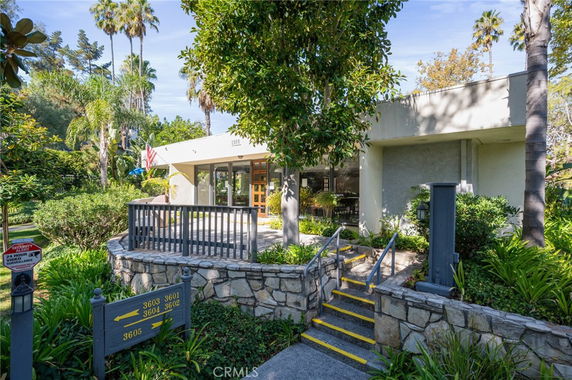 Front view of a modern, single-story building with large glass windows and surrounding greenery.