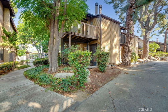 Front view of a two-story residential building with wooden exterior and a balcony.