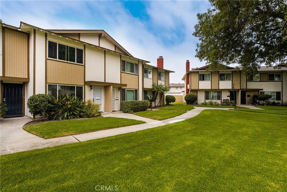 Front view of multiple two-story houses with similar design, featuring large windows and pathways.