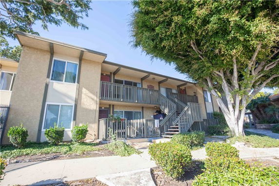 Front view of a two-story apartment building with balconies and an exterior staircase.