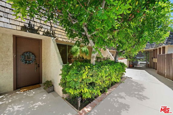 Front view of a house entrance with a wooden door and surrounding greenery.