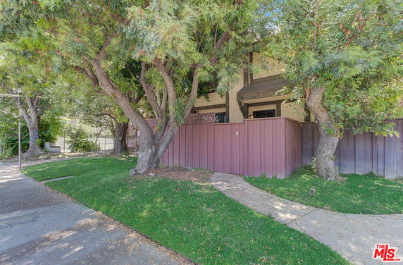 Front view of a house with a wooden fence and trees in front