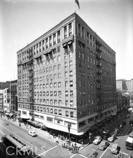 Front view of a multi-story building with multiple windows and a flag on top.