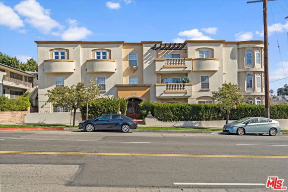Front view of a multi-story residential building with balconies and bay windows.