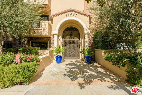 Front view of a building entrance with an arched gateway and decorative plants.