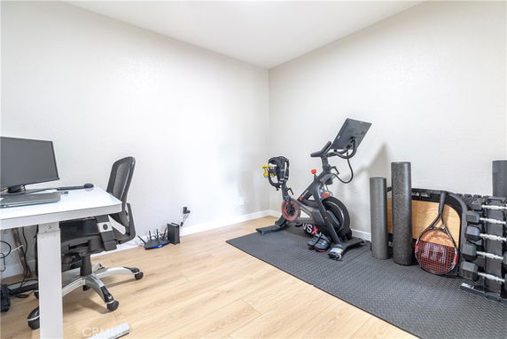 Room with exercise equipment and a desk with a computer.