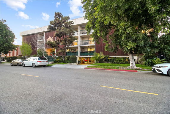Front view of a multi-story building with balconies and a covered entrance.