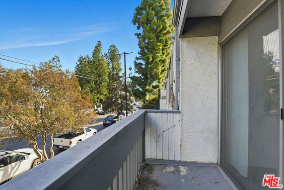 Balcony view showing a street with cars and trees.
