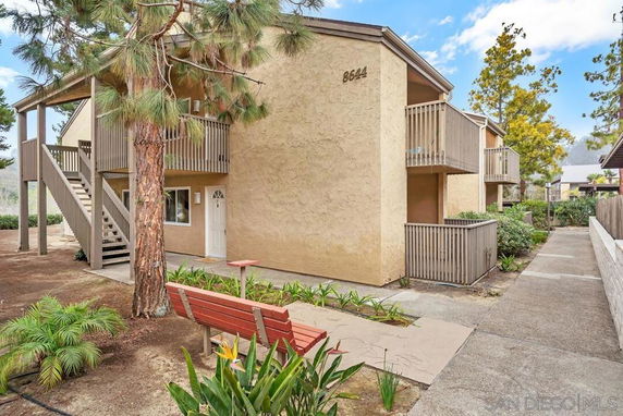 Front view of a two-story apartment building with balconies and an external staircase.