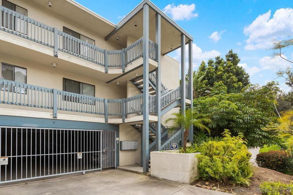 Front view of a multi-story building with balconies and external staircase.