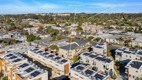 Aerial view of a residential neighborhood with multiple buildings and a golf course in the distance.