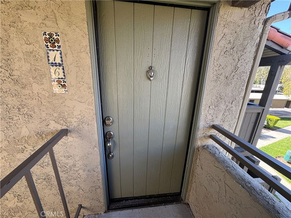 Front entrance view of a house with a green door and decorative tiles.