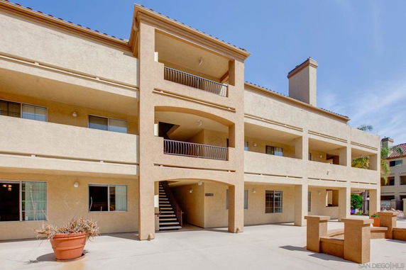 Front view of a multi-story residential building with balconies and a staircase.