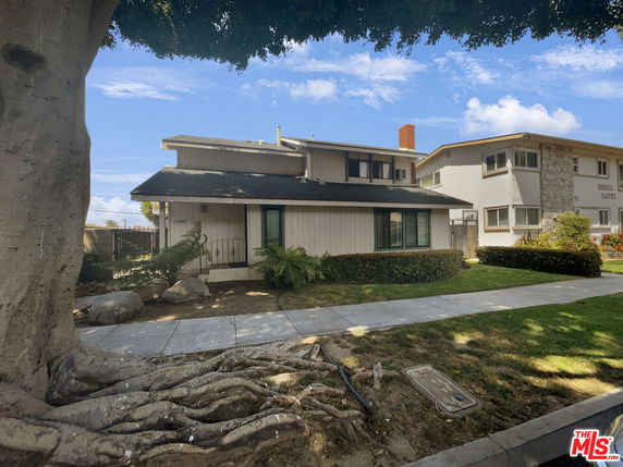 Front view of a two-story house with a tree in the foreground.