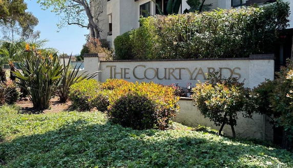 Front view of a building with a sign reading 'The Courtyards' and surrounded by landscaped greenery.