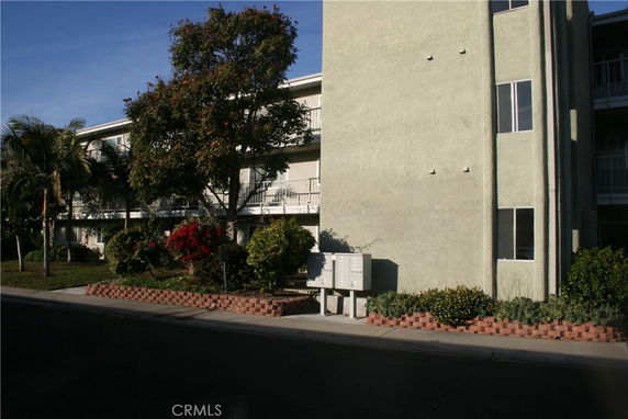 Front view of a multi-story building with balconies and landscaped garden.