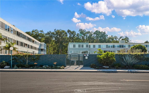 Front view of a multi-story residential building with a gated entrance.