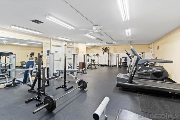 Indoor gym area with various exercise equipment including treadmills and weights.