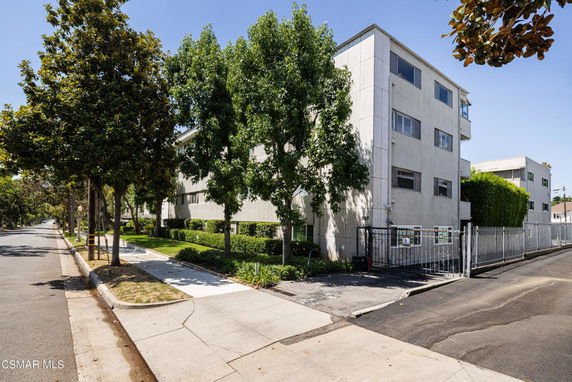 Front view of a multi-story apartment building with a gated entrance.