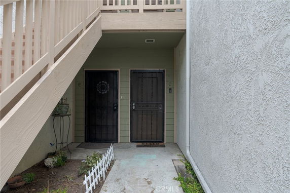 Entrance view of a building with two doors and stairs overhead.