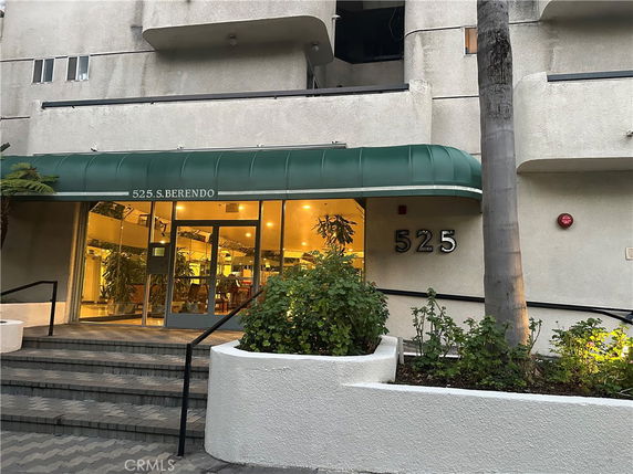 Front view of a multi-story building with a green awning and a glass door entrance.
