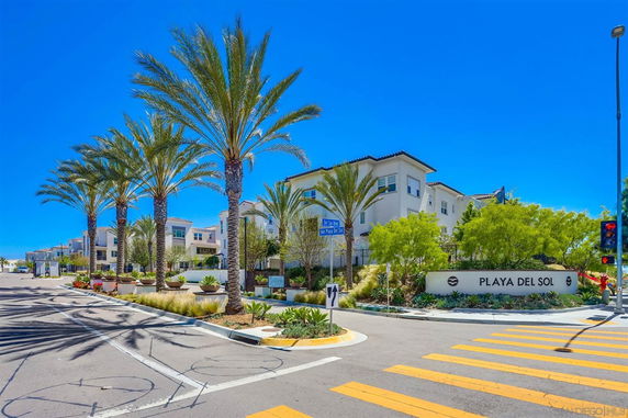 Front view of a residential complex with palm trees lining the entrance.