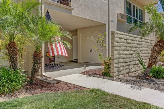 Front view of a modern house entrance with a covered patio and an American flag.