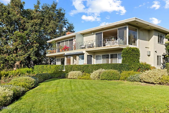 Front view of a two-story house with a balcony and large windows.