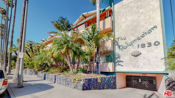 Front view of a multi-story building with distinctive architectural design and lush landscaping.