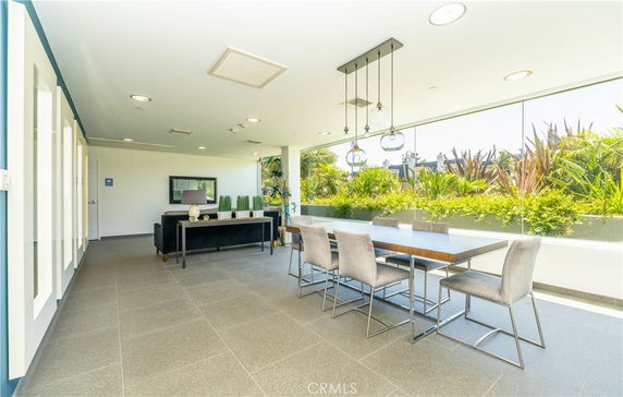 Interior view of a modern clubhouse with a seating area and dining table near a large window.