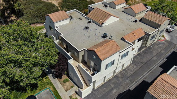 Aerial view of a building with a flat rooftop featuring air conditioning units and a ladder.