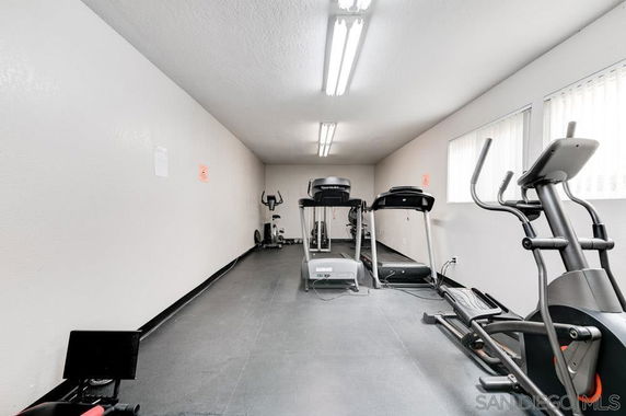 Room with exercise equipment including treadmills and stationary bikes.