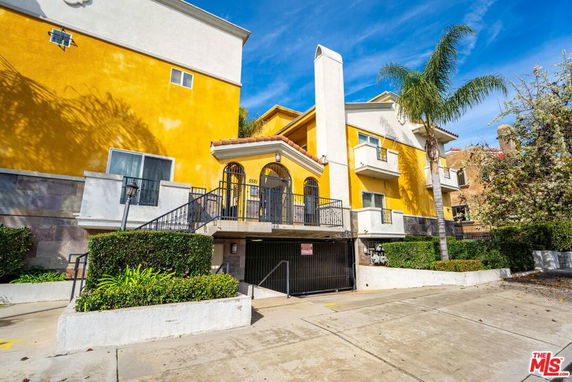 Front view of a yellow multi-story building with a gated entrance.