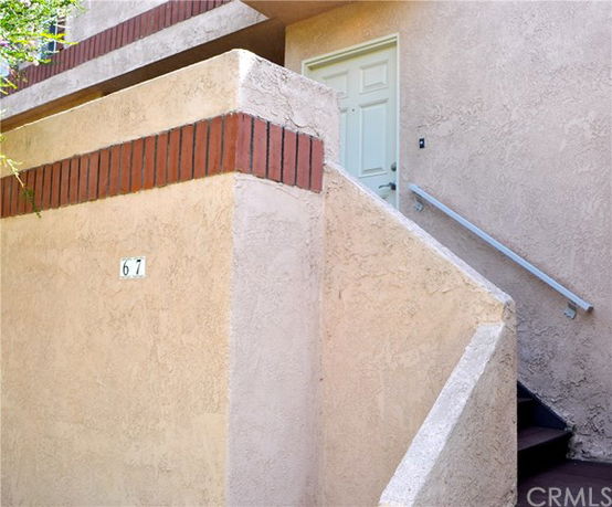 Front view of a building entrance with stairs leading up to a white door.