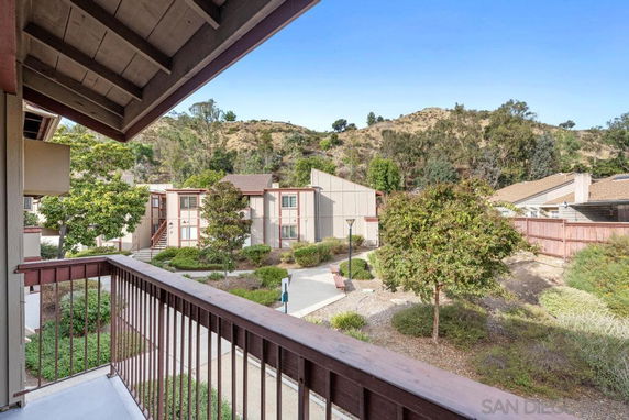 View from a balcony overlooking residential buildings and surrounding landscape.