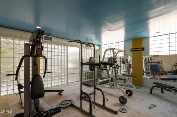 Indoor gym area with fitness equipment and mirrored walls.