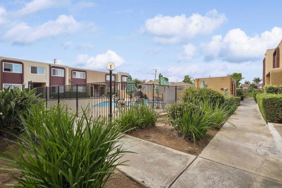 Outdoor swimming pool area surrounded by apartment buildings and greenery.