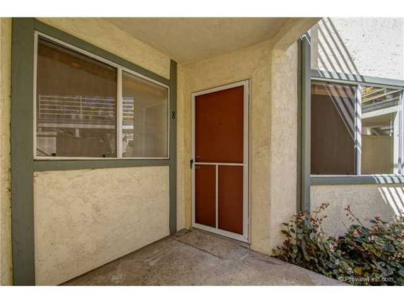 Outdoor entrance corner of a building with windows and a red door.