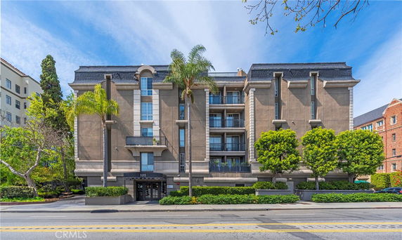 Front view of a multi-story building with balconies and landscaped surroundings.
