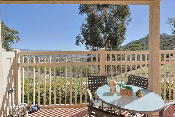 View of surrounding areas with hills seen from a patio with a table and chairs.