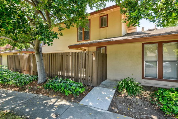 Front view of a two-story house with a wooden fence and walkway.