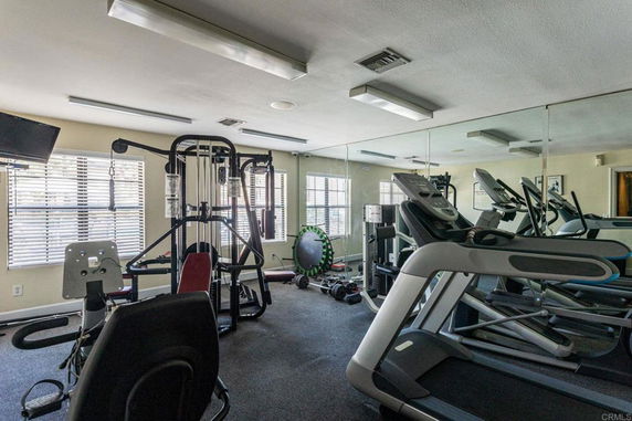 Room equipped with various gym equipment including treadmills and weight machines.