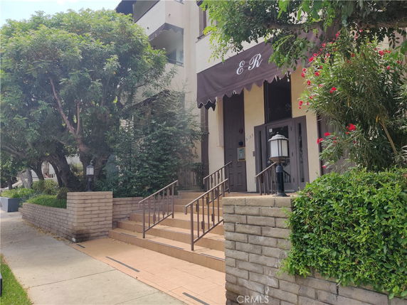 Front view of a multi-story building with an awning and entrance steps.
