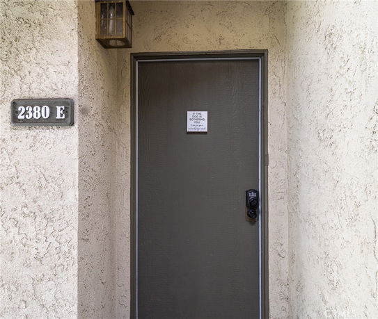 Front view of a residential entryway with a brown door and address plaque.