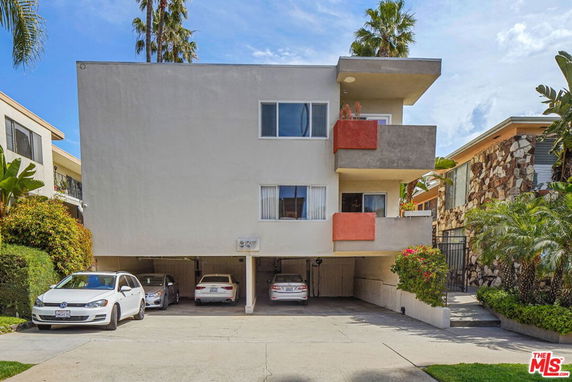 Front view of a multi-story building with open parking spaces on the ground level.
