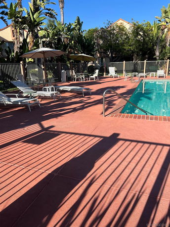 Outdoor swimming pool area with lounge chairs and umbrellas.
