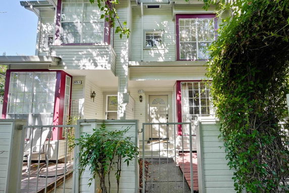 Front view of a two-story house with large windows and a small gated entrance.
